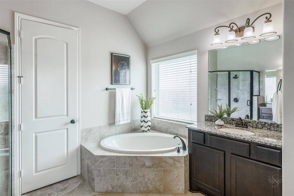 The primary bathroom features a relaxing garden tub and a spacious shower, creating a luxurious retreat. A generous granite countertop completes the space, leading seamlessly into a large walk-in closet for added convenience.