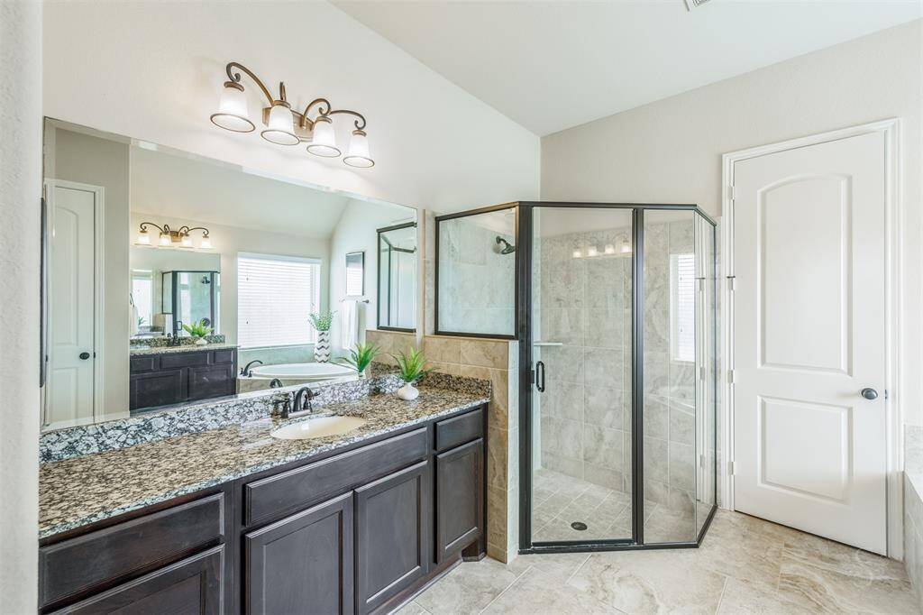 The primary bathroom features a relaxing garden tub and a spacious shower, creating a luxurious retreat. A generous granite countertop completes the space, leading seamlessly into a large walk-in closet for added convenience.