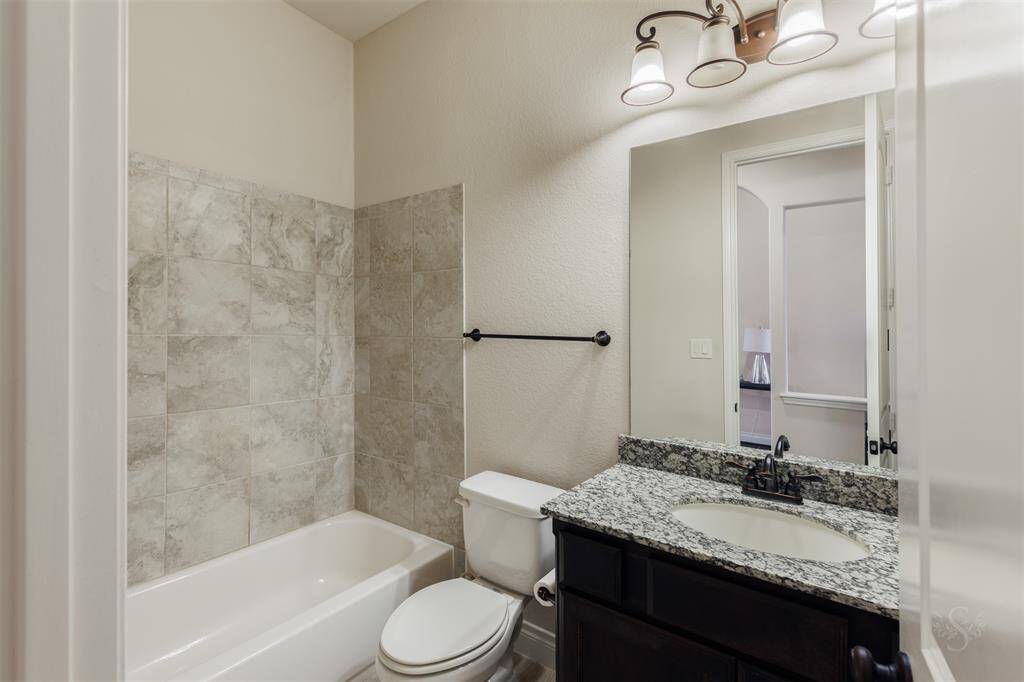 The secondary full bath provides a vanity counter, accent lighting and shower/tub combo with neutral tile backsplash.