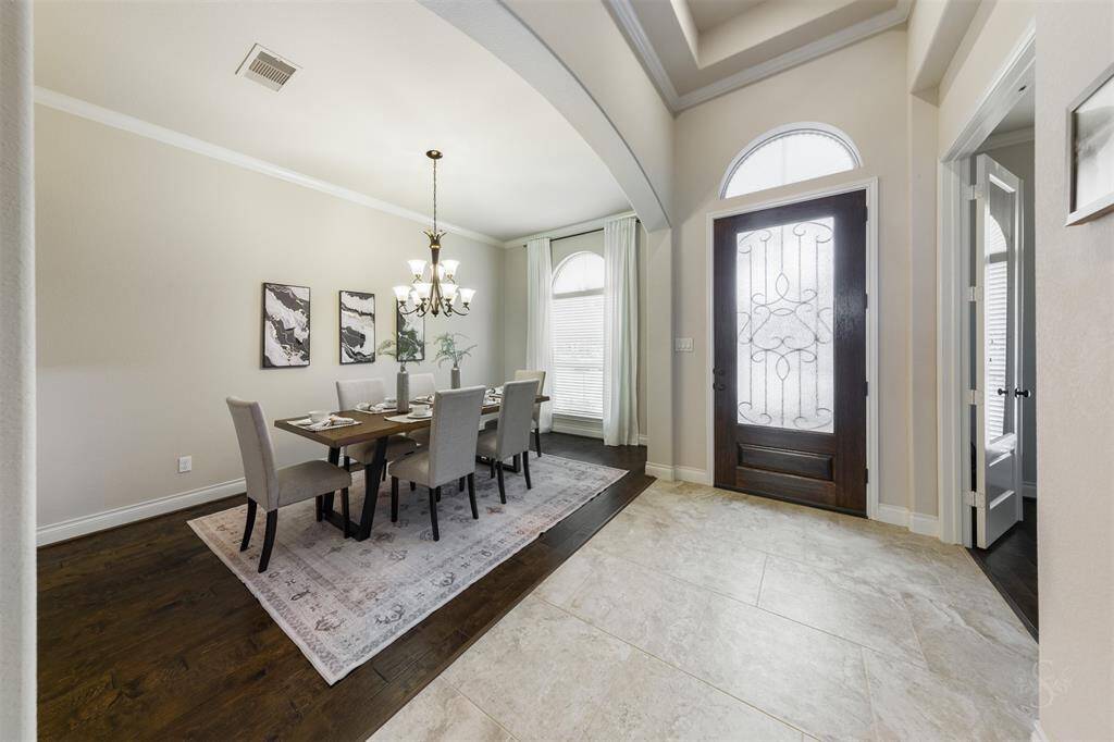 Stepping through the front door, you're greeted by high tray ceilings that make the entrance feel grand yet inviting. Just beyond, the formal dining room boasts rich wood flooring, arched entry, high ceiling with crown molding and perfect for hosting memorable gatherings in style.