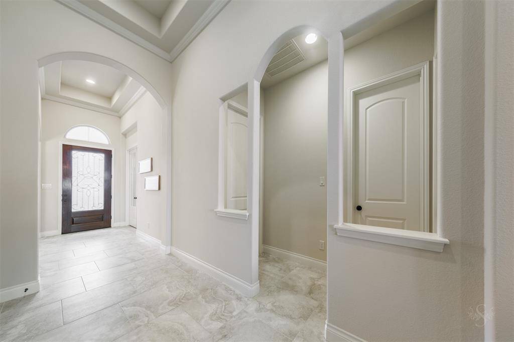 The hallway stretches ahead, highlighted by elegant tray ceilings that add a touch of sophistication to the space. On the left, you'll find two cozy secondary bedrooms, each offering plenty of comfort and privacy.