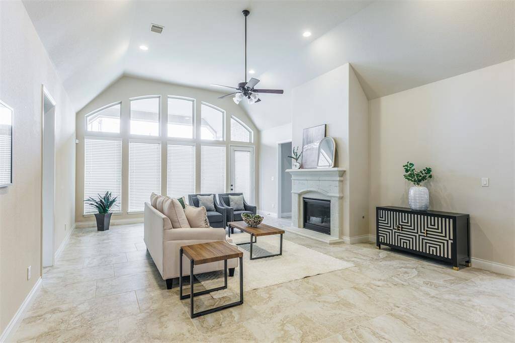 The family room boasts a wall of windows that flood the space with natural light, creating a bright and airy atmosphere. High angled ceilings and recessed lighting add to the room's sense of openness and elegance, making it the perfect place to relax and gather.