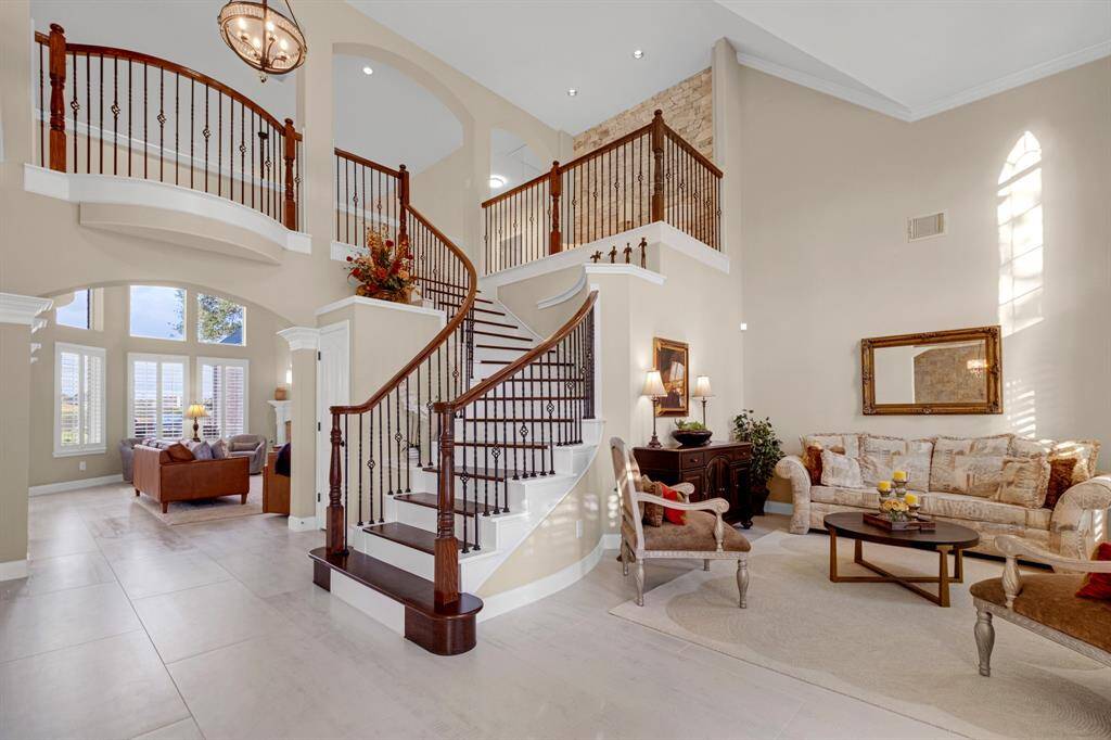 Elegant living space features high ceilings, an open staircase with wood and wrought-iron railings, and abundant natural light from large windows. ***OVER  $225,000 IN UPGRADES IN THE LAST YEAR***