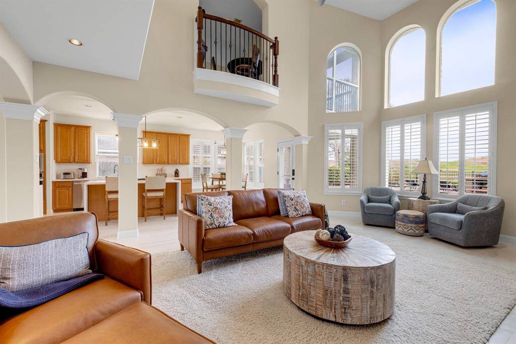Spacios and well-lit living room and high ceilings, large windows, and an open floor plan that flows into newly remodeled kitchen area. It features a cozy fireplace.