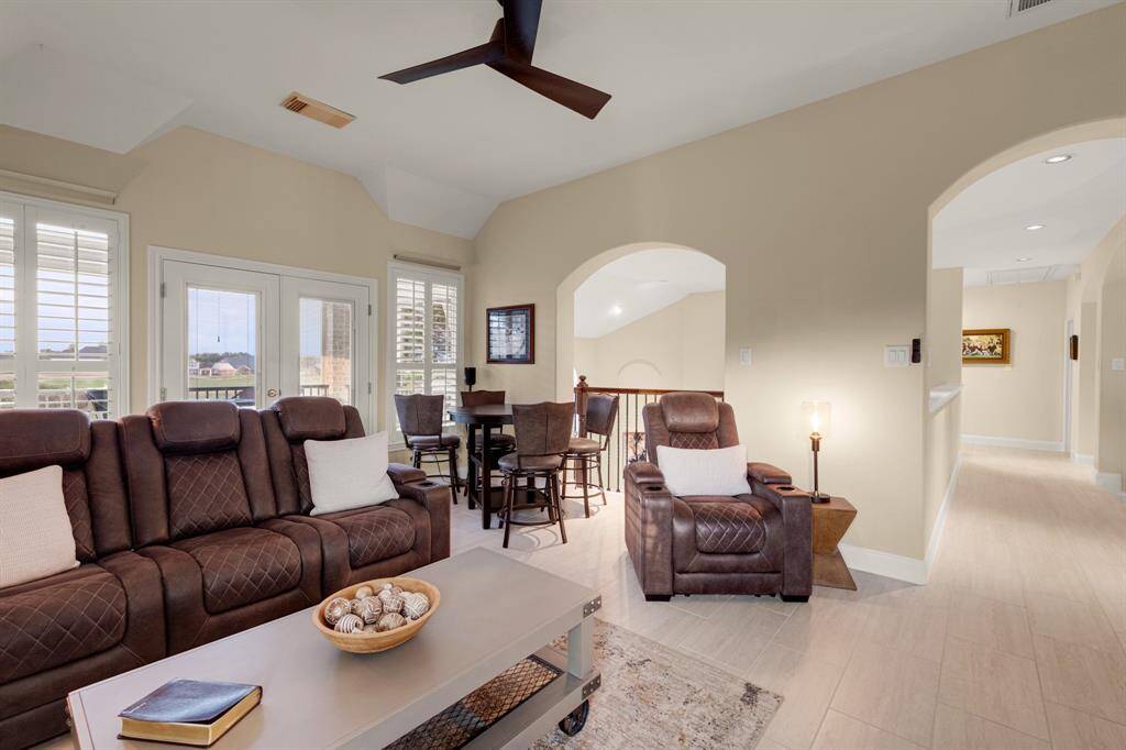A spacious and inviting living room with high vaulted ceilings, large windows with plantation shutters, creating a warm and welcoming atmosphere.   1'x2' porcelain tile flooring.