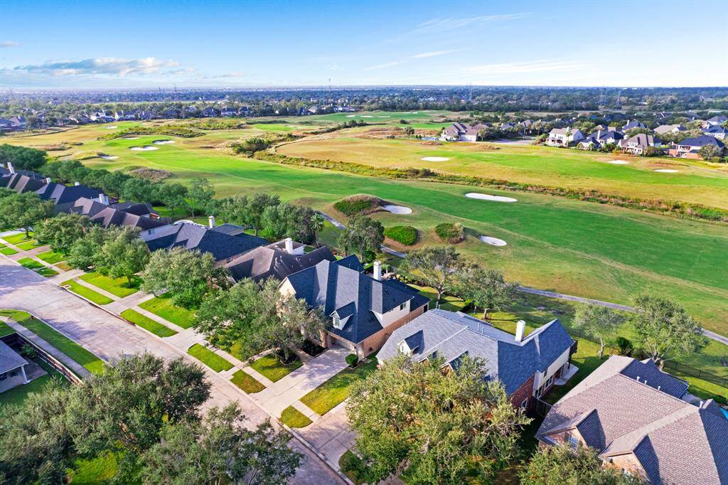 Aerial view of a residential area with spacious homes adjacent to a lush golf course, offering a serene and green living environment.