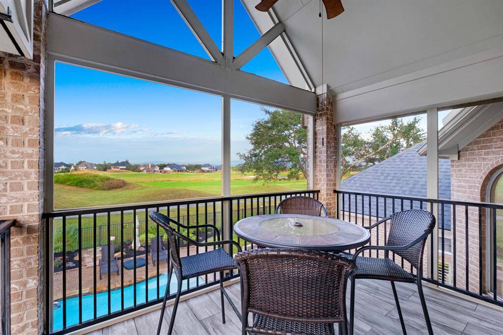 A covered patio with a high vaulted ceiling, offering panoramic views of a golf course and a glimpse of a private pool, perfect for outdoor relaxation and entertainment.  Incredible view of the rolling links