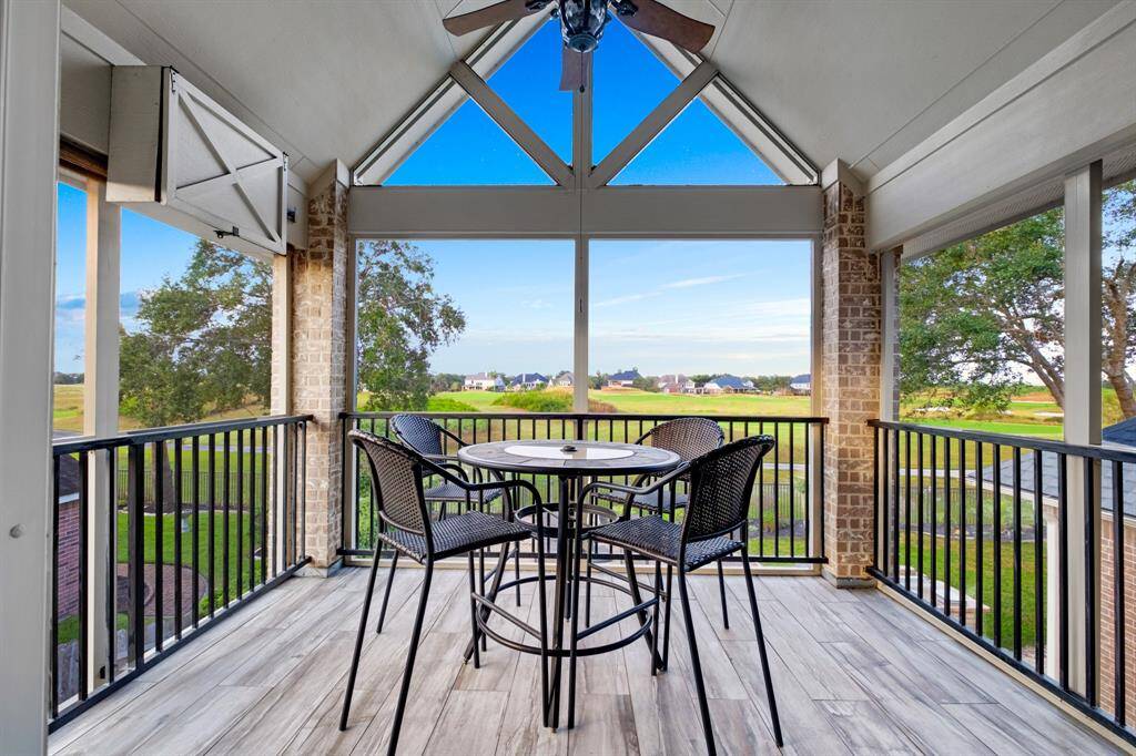 A spacious screened-in patio featuring a high ceiling with fan, tile flooring. It offers a panoramic view of a serene landscape and a well-maintained lawn. Ideal for outdoor dining or relaxation while protected from the elements.  Fabulous view of the rolling hills of the 6th hole.