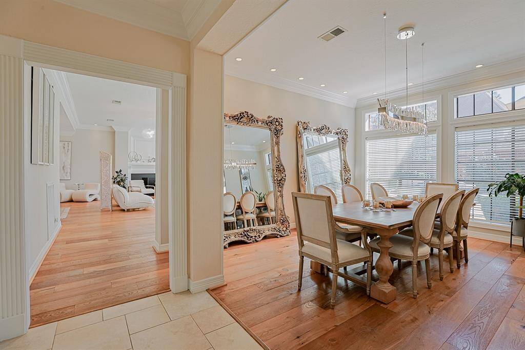 A sophisticated dining space featuring a statement chandelier, large windows, and elegant furnishings. The warm wood flooring and high-end finishes make it the perfect setting for hosting memorable dinners.
