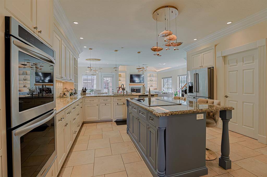 A chef's dream kitchen with an oversized island, granite countertops, custom cabinetry, and high-end stainless-steel appliances. The open-concept layout seamlessly connects to the living and dining areas, making it ideal for entertaining.