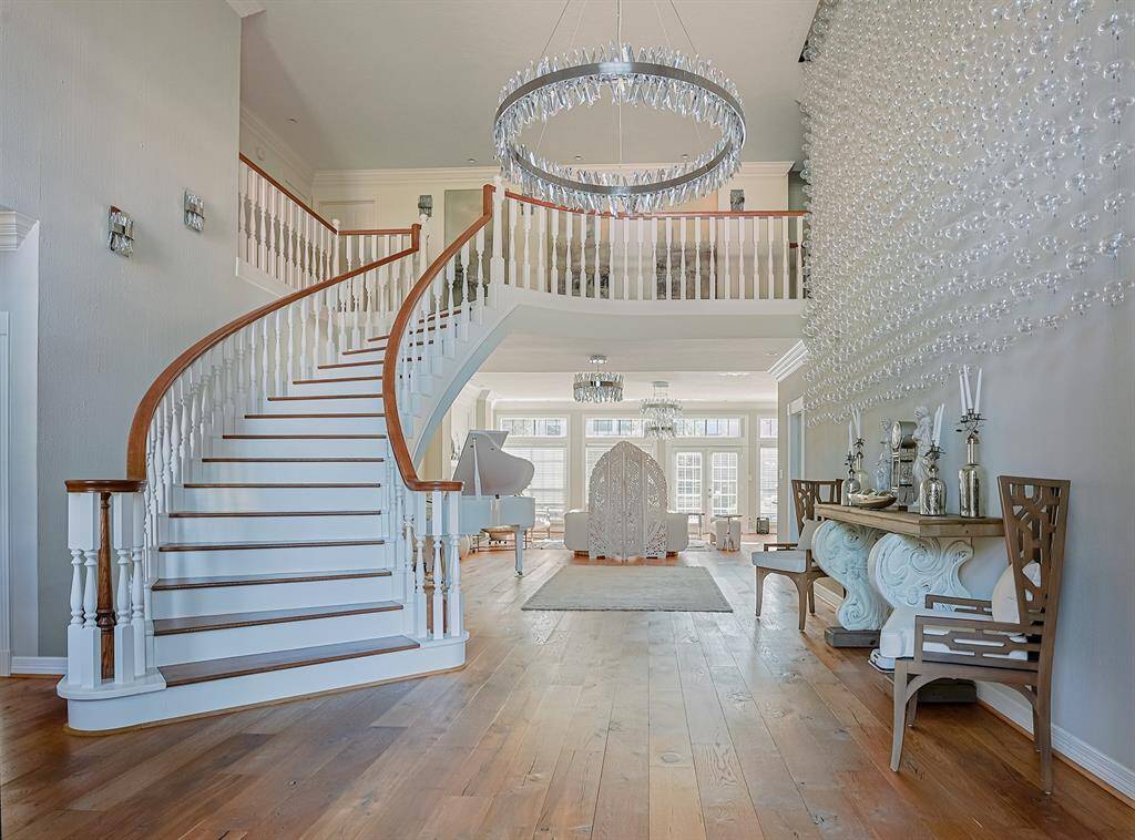 A breathtaking curved staircase with wooden handrails and white balusters serves as a stunning centerpiece in the home’s grand foyer. The soaring ceilings and open layout add to the sense of grandeur, while natural light highlights the beauty of the hardwood floors.