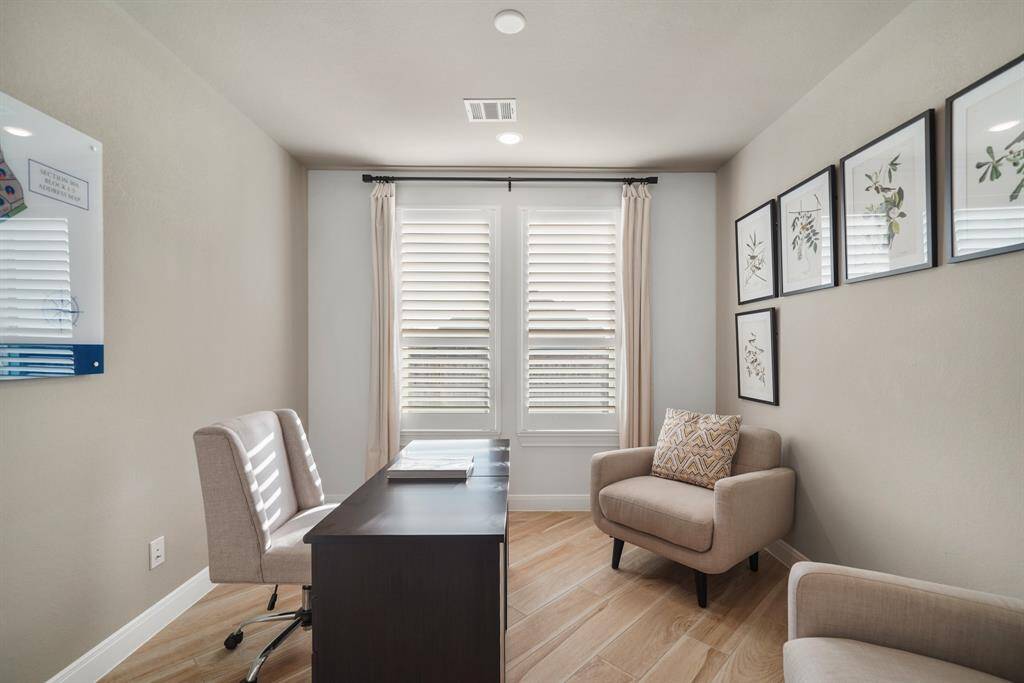 The perfect work-from-home retreat, this home office features large windows, flooding the space with natural light while plantation shutters add timeless charm.