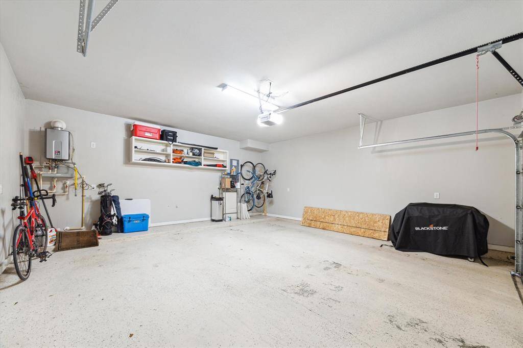 This garage features ample storage with wall-mounted shelves, a water heater, and a clean, organized layout. Ideal for parking and extra storage needs.