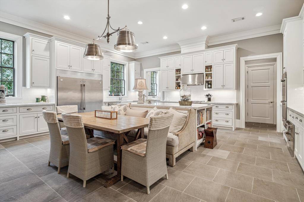 The breakfast room is large enough to seat six and is surrounded by white cabinetry, subtle grey tile and light filled windows.
