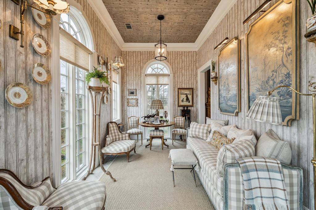 The sun room enjoys views of the tree lined property and lush gardens.