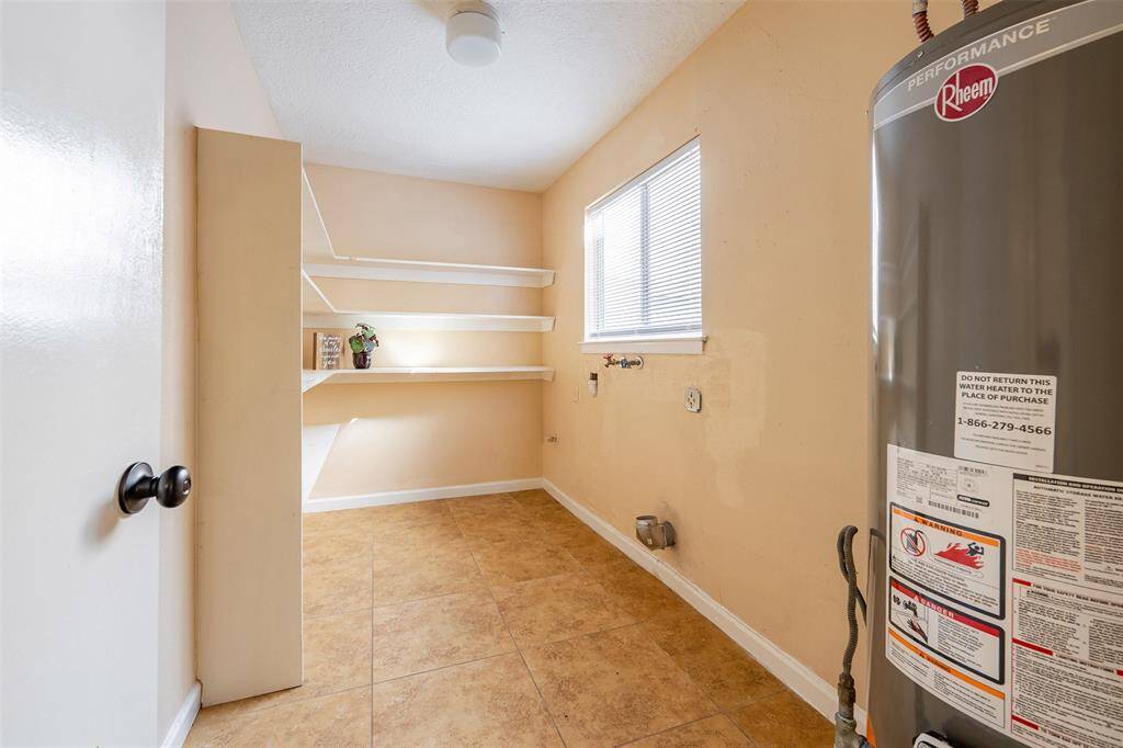 The extra-large laundry room, located just off the kitchen, features shelving space that doubles as a pantry, providing added convenience and storage.