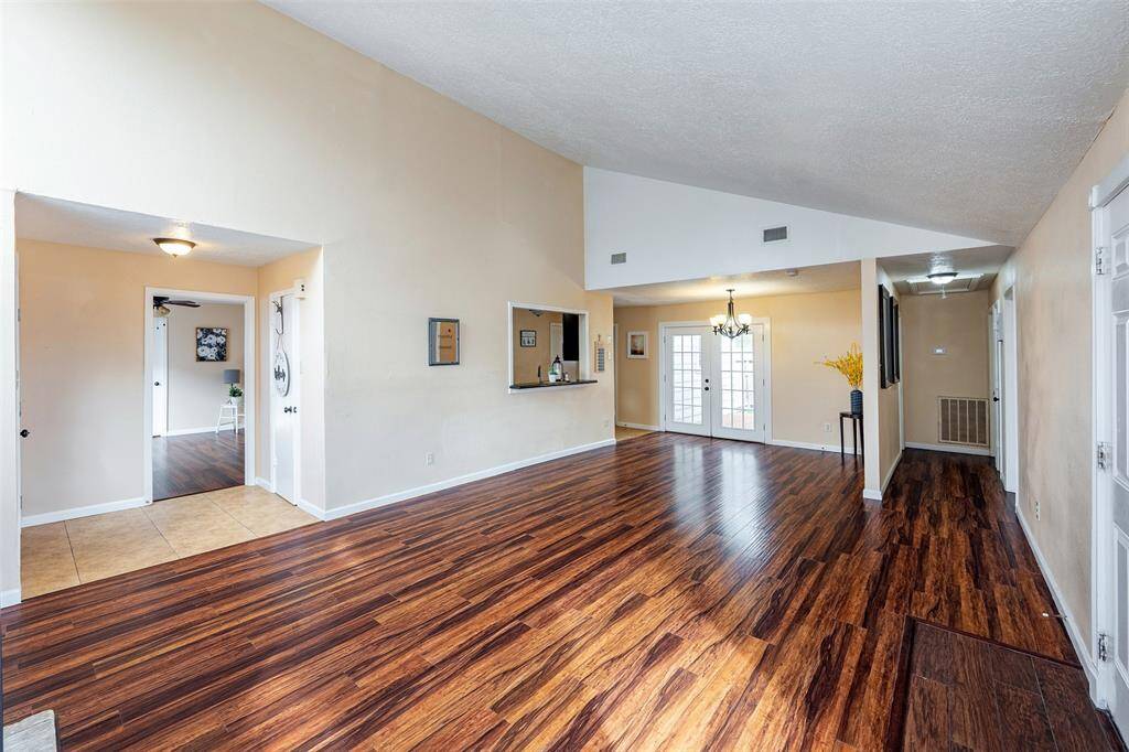 The living room is seamlessly connected to the formal dining area in this open layout. To the left are the master bedroom and kitchen, and the right side features two additional bedrooms for privacy and convenience.