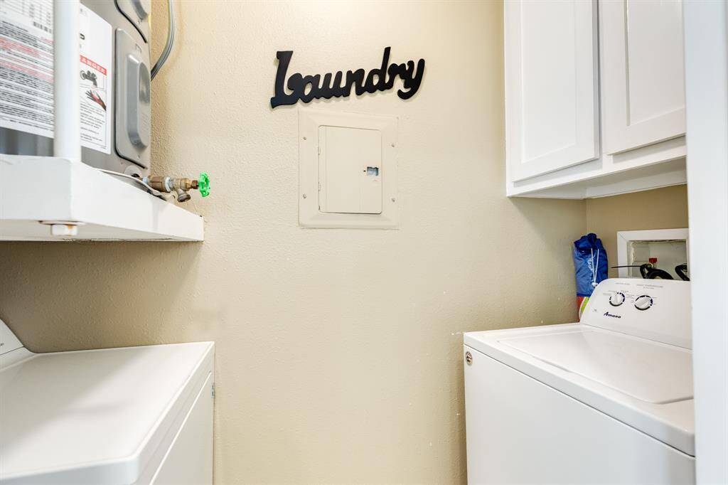 Utility room with full size washer & dryer, hot water heater and storage cabinet.