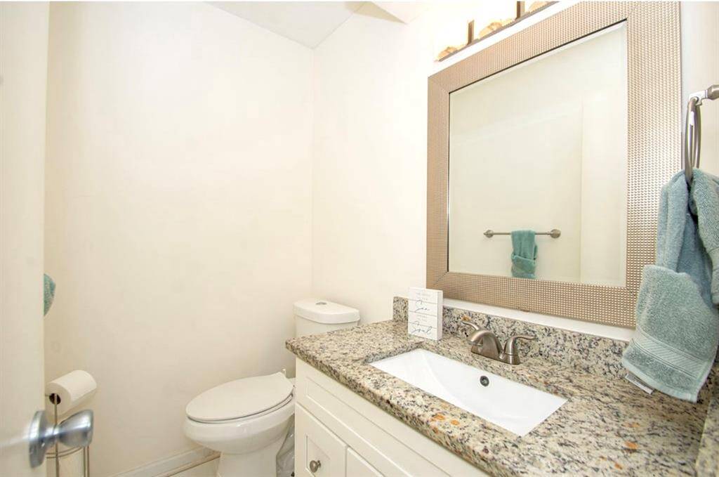 This updated powder room is located by the kitchen and features updated cabinetry, granite, undermount sink, mirror, lighting and commode!