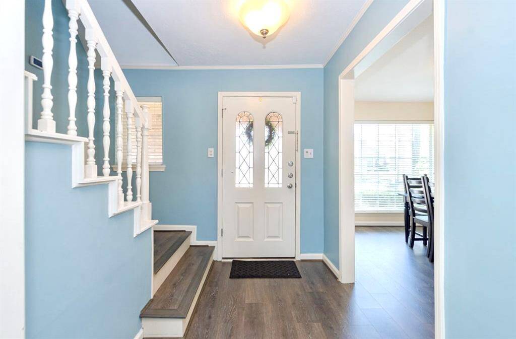 This entryway is so warm and inviting with an updated light fixture, 2024 luxury vinyl plank flooring that covers the stairs and upstairs hallway, as well 2023 LVP in the entry, dining, family and owner bedroom! A coat/storage closet is located under the stairwell to the left!