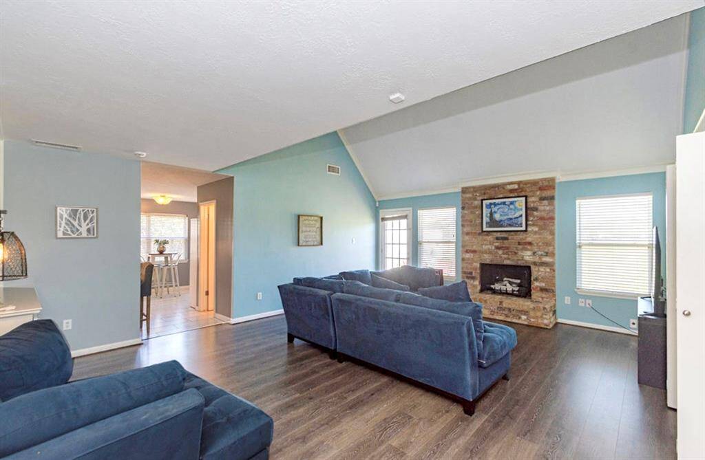 The Family Room is so spacious and features high ceilings, a warm brick Gas Logs Fireplace, and abundant natural light! The open layout flows into kitchen area! The room is accented with soothing blue walls and updated LVP flooring!