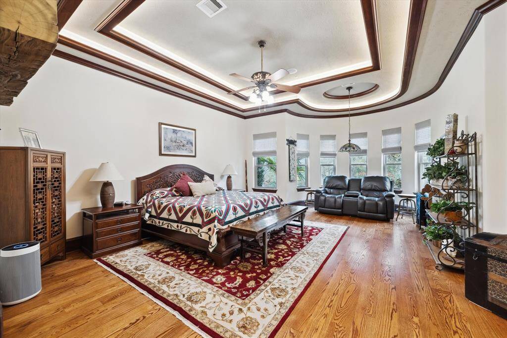 The spacious primary bedroom on the first floor is privately tucked away.  Featured is an intimate sitting area with a Tiffany hanging lamp. There is an oversized walk-in closet with 2 built in dressers, and a central island with two hidden drawers.  There is also a built-in jewelry/accessory storage cabinet in the closet.