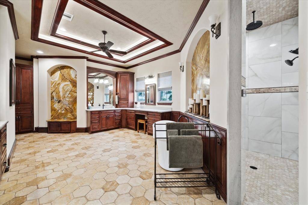 This photo focuses on the extensive upgrades in the primary bathroom; the ceiling, flooring, custom built-ins and natural lighting