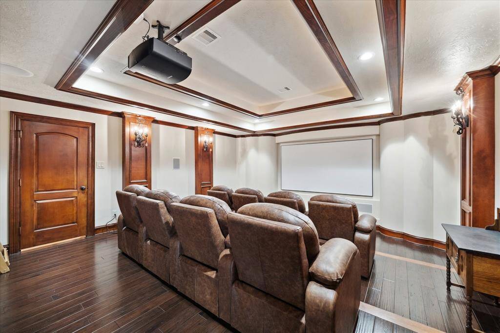 This home theater features 8 plush power theatre chairs on two stair step platforms and elegant wood paneling. The room is equipped with a 4k Sony ceiling projector and screen creating a cozy and immersive entertainment space.