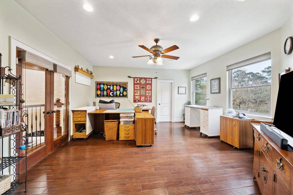 This spacious, well-lit second floor bedroom is used as a crafts room/sewing area.  It features hardwood floors, multiple large windows offering natural light, and a ceiling fan. It's ideal as a bedroom, office or creative space, with ample areas for appropriate furniture.