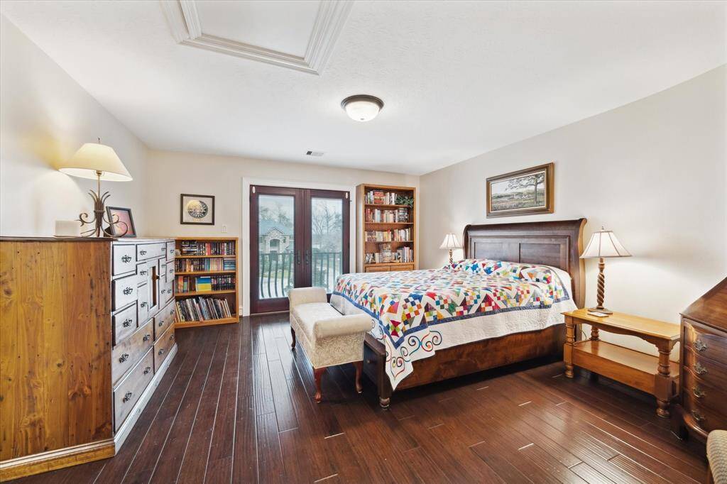 Another spacious and bright secondary bedroom with wood flooring, with ample areas for furniture. There is an ensuite bathroom  The room includes a large window with a view and direct access to a small balcony, perfect for enjoying fresh air.