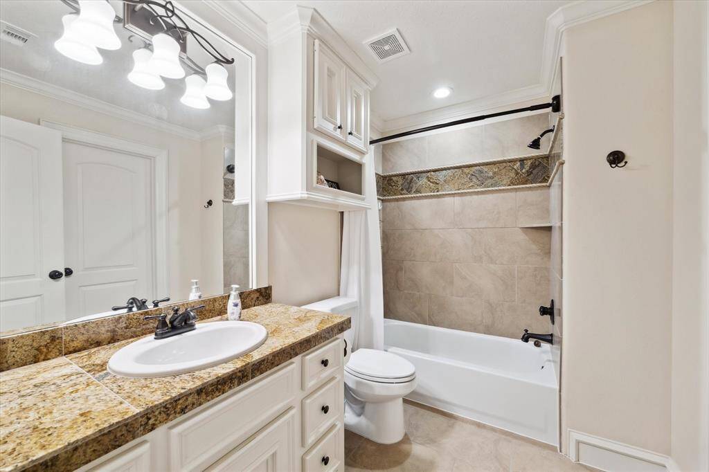 Another ensuite bathroom with a sink, granite countertops and a shower/tub combination