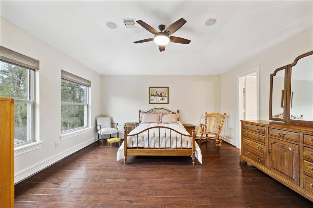 This is a third bedroom on the second floor with hardwood floors and large windows providing natural light. It features a ceiling fan and provides an warm and inviting atmosphere.