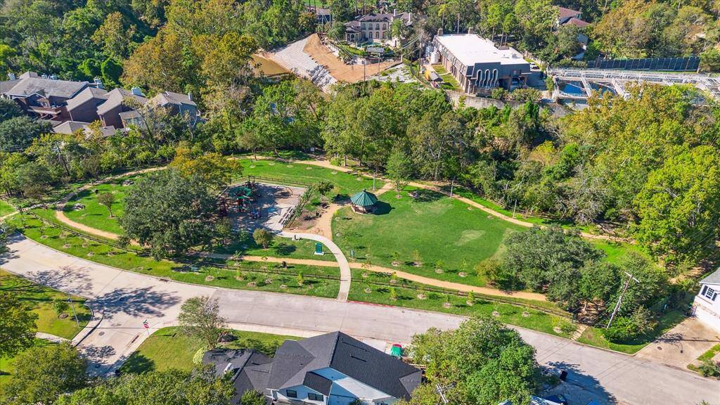 This aerial photo showcases a spacious park featuring walking paths, recently replaced playground equipment, canoe/kayak launch, upgraded lighting, open green spaces, and mature trees. The surrounding area includes shopping, restaurants, churches and offers a blend of nature and community living. Ideal for buyers seeking a peaceful and scenic environment.