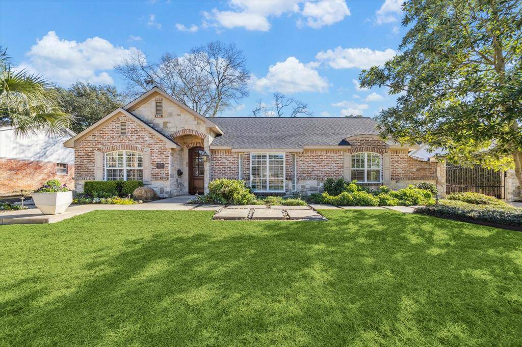 Charming brick home with a welcoming front porch and manicured lawn. Features large arched windows, a well-maintained garden, and a spacious driveway. Ideal for a cozy and inviting living environment.