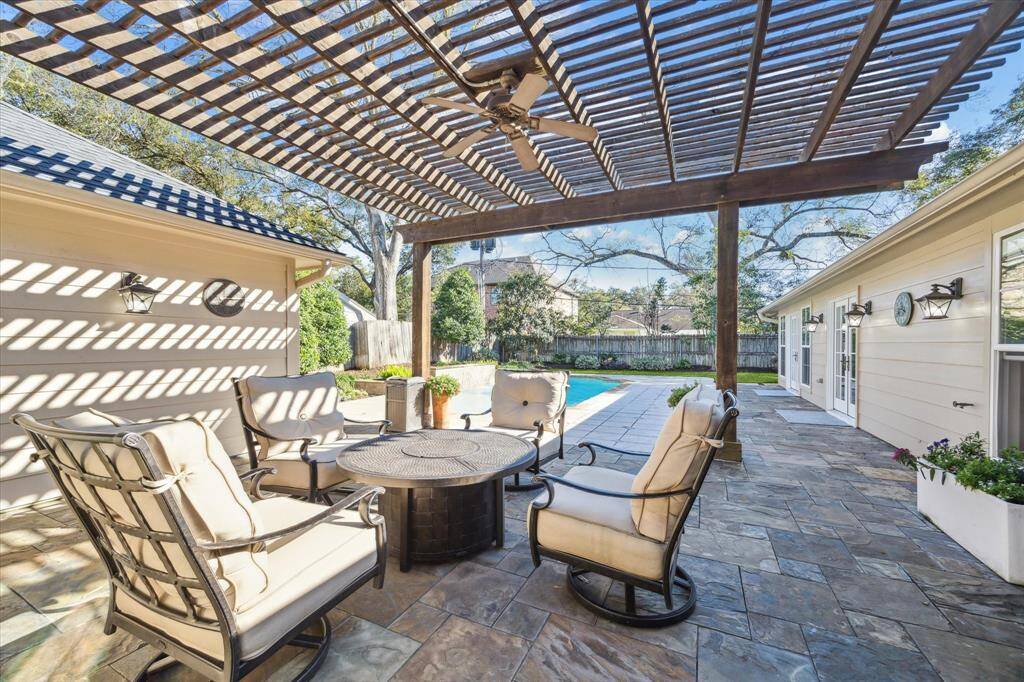 This photo showcases a spacious outdoor patio with a pergola and overlooks a well-maintained backyard with a heated swimming pool with water features offering a perfect setting for relaxation and entertainment.