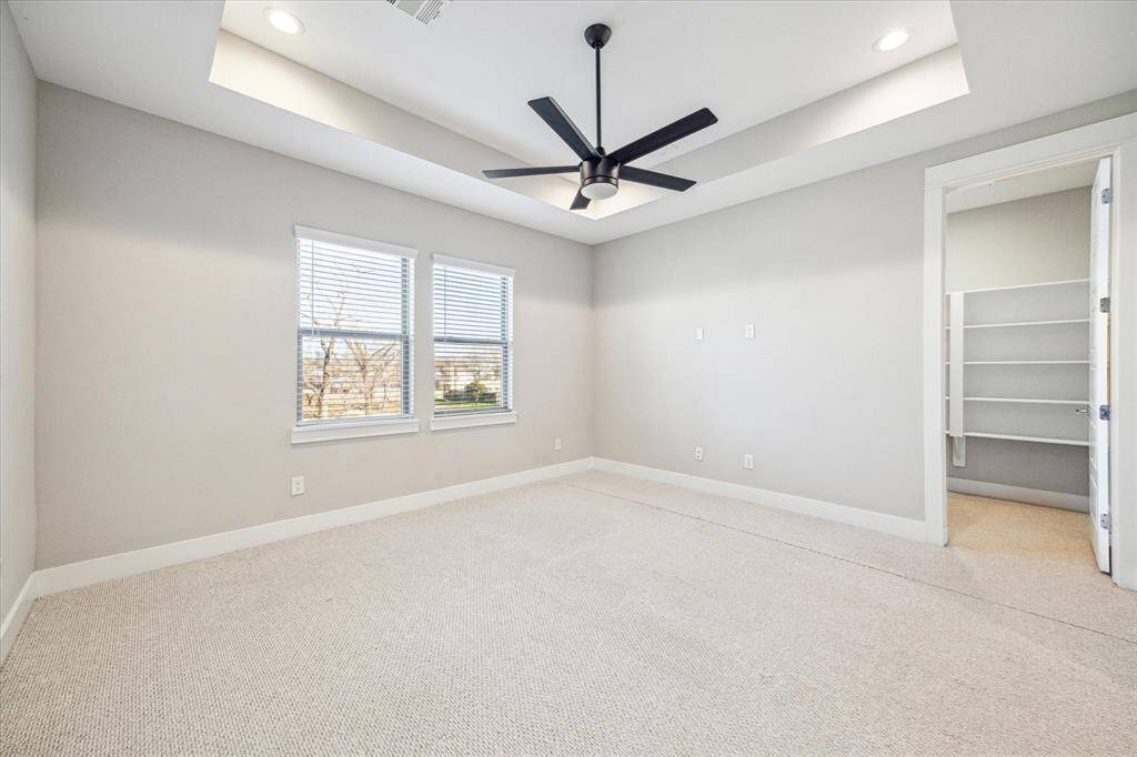 Spacious primary bedroom with tray ceiling and walk-in closet.