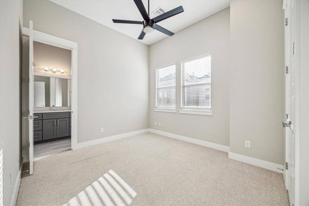 Secondary bedroom with ceiling fan and view of shared bath.