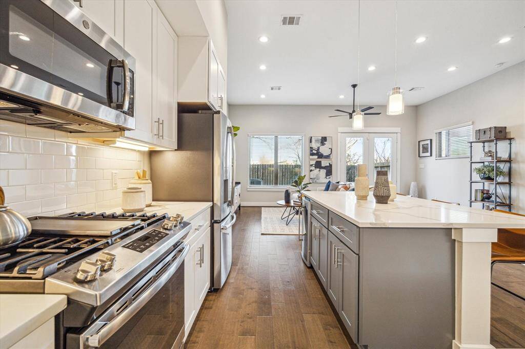 Clean, crisp lines define the kitchen. The range has a six-burner cooktop and there is a wine cooler in the island.