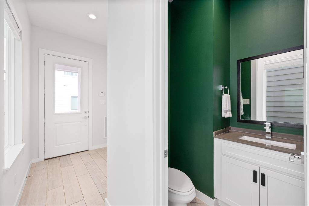 Half bathroom just off the entryway features designer paint colors, new herringbone laid tile flooring.