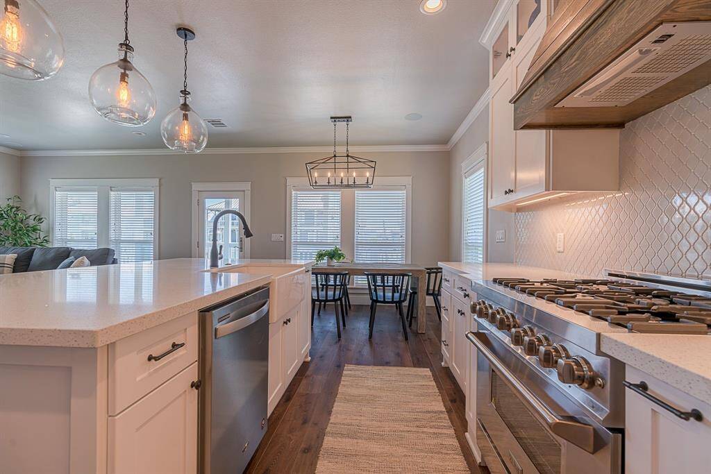 Gourmet kitchen with stainless steel appliances, gas range and custom vent hood