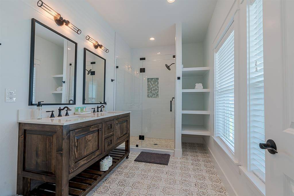Primary bath with beautiful double sink vanity, stand alone fully tiled shower, and designer tile. Plenty of storage.