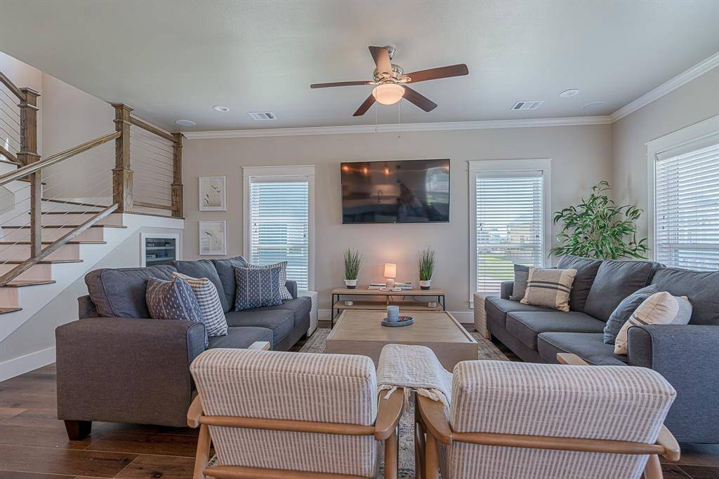 Living room space with ceiling fan, cased windows and under stairs storage.