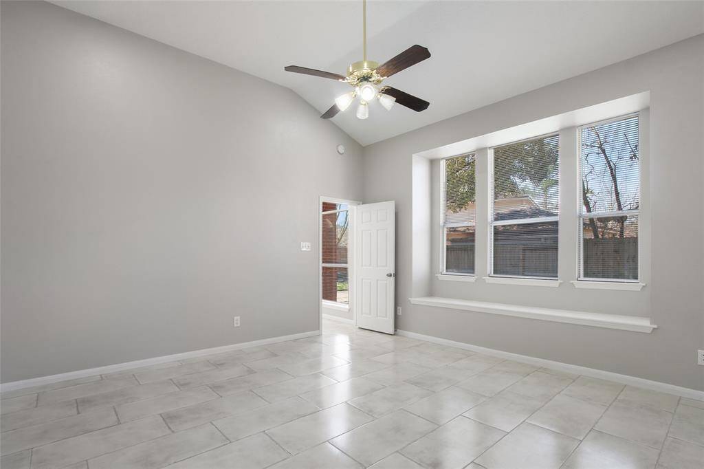 This room features high ceilings and a ceiling fan, with large windows that provide plenty of natural light. The neutral-colored walls and tiled floor create a spacious and modern feel.