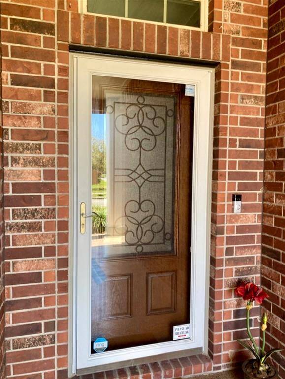 A closer view of the beautiful iron and glass front door, storm door and Ring Door Bell.