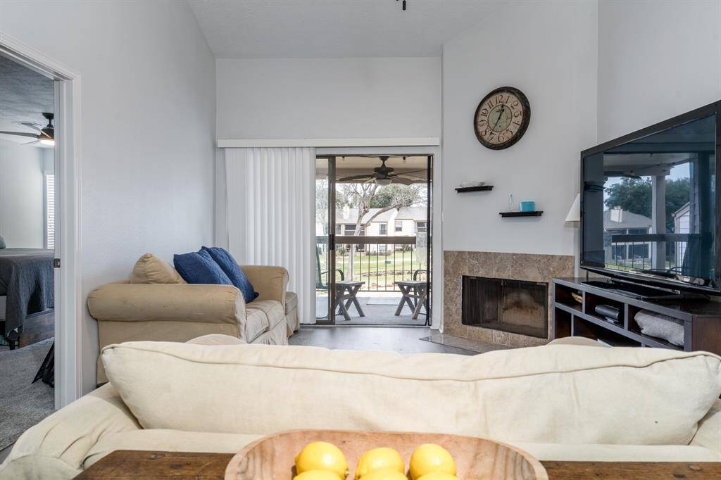 Another view of the living room with fireplace, patio, and the primary bedroom to the left.