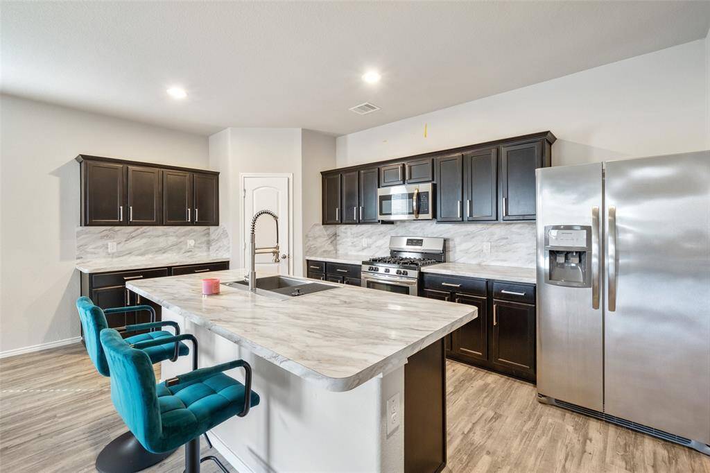 The kitchen is designed with convenience in mind, featuring a gas range, a spacious center island with breakfast bar seating
