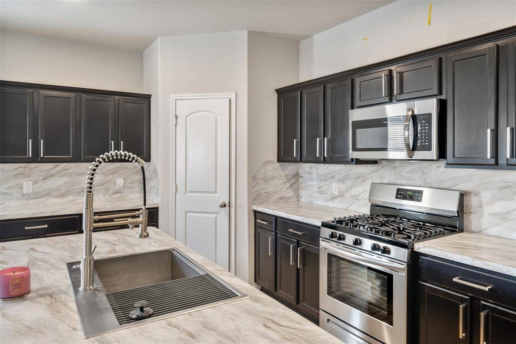 Stainless steel appliances and hardware and a walk-in pantry complete this functional and well-equipped space.