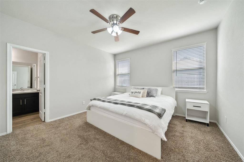 The spacious primary suite is a true retreat, featuring large windows that let in soft natural light.