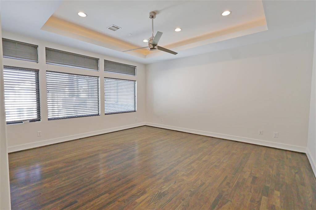 The spacious primary bedroom boasts elegant tray ceilings, custom lighting, abundant natural sunlight, and recessed lighting, creating a bright and luxurious retreat.