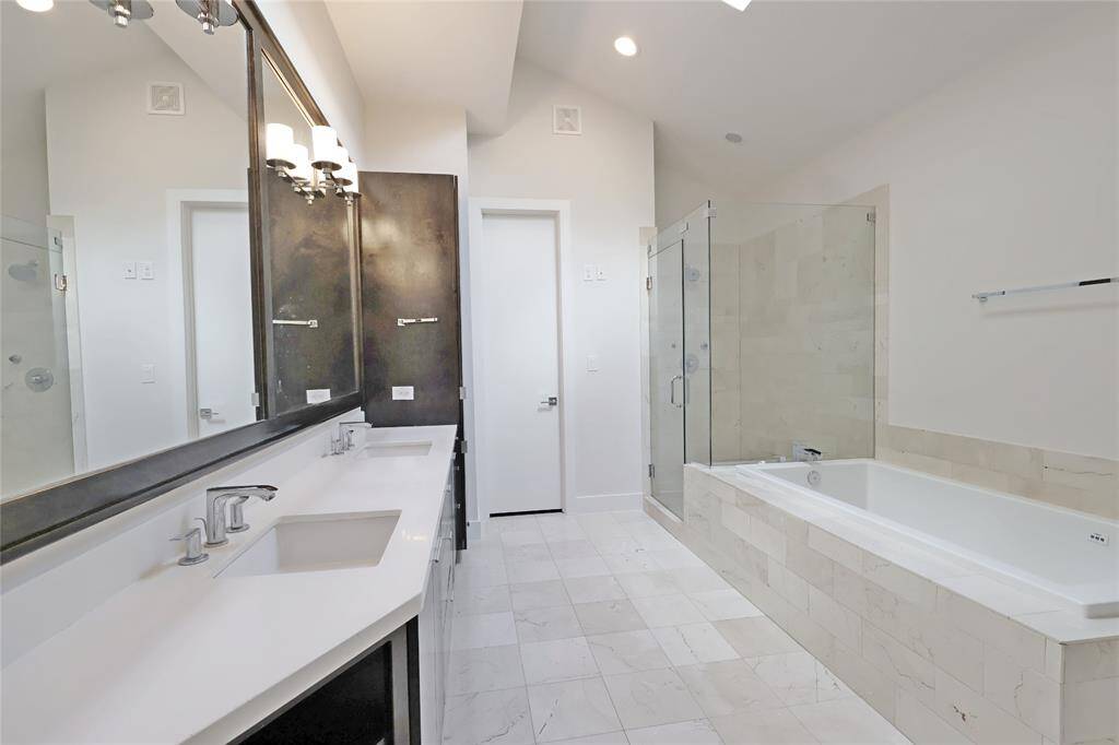Separate tub and shower, and a spacious stand-up shower with body sprayers and a stylish tile backsplash.